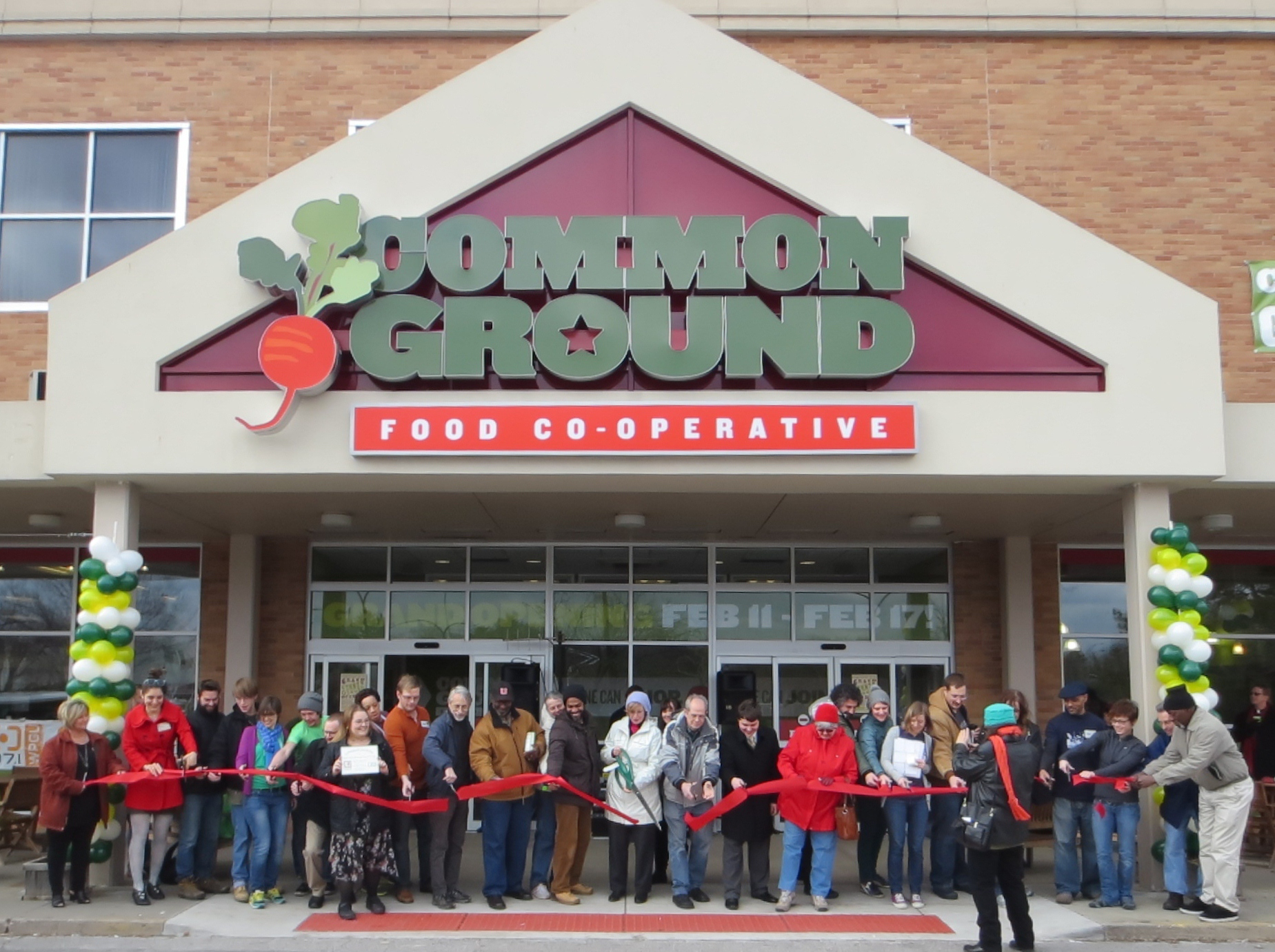 Common Ground staff and community members cutting the ribbon to celebrate the grand opening of the newly expanded co-op. 